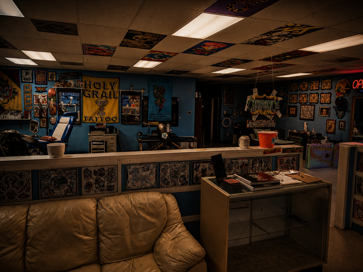 The lounge at A Holy Grail Tattoo with a leather couch beneath walls of flash art