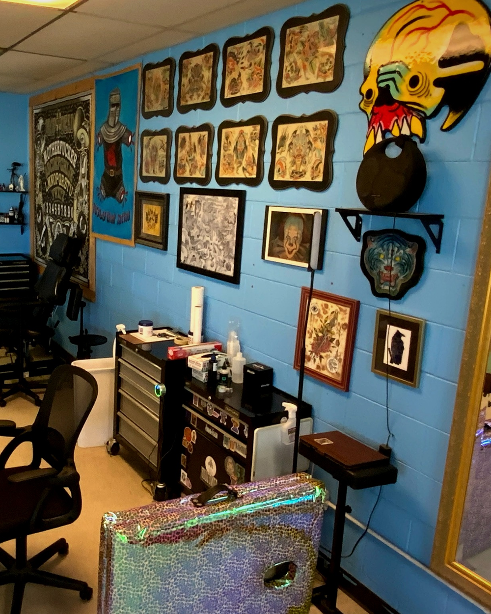 A tattoo room with a mint chair, skull artwork, and a Ouija tapestry