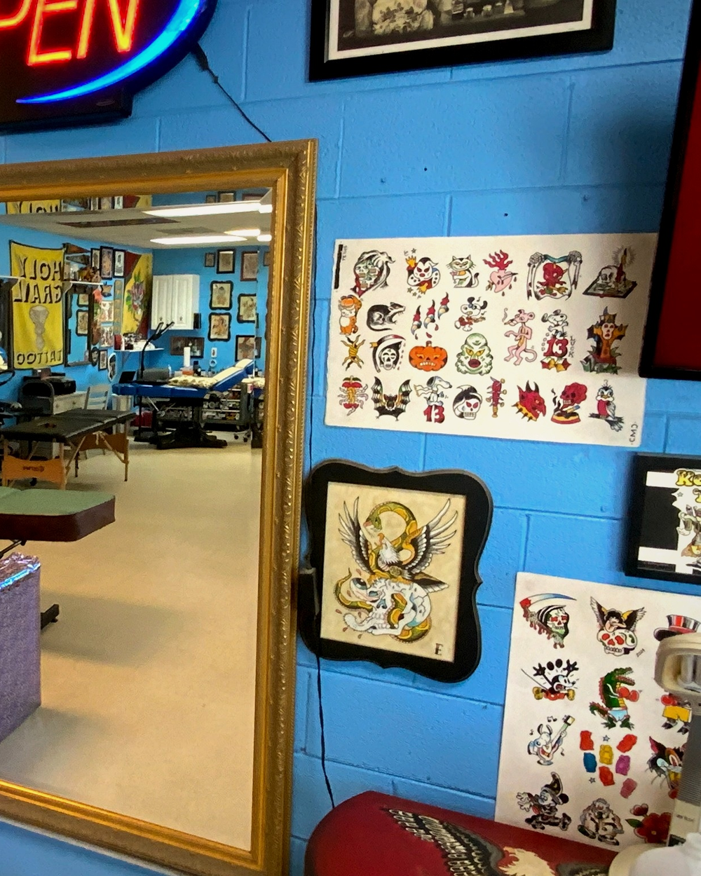 A gold-framed mirror reflecting the studio interior beside flash art