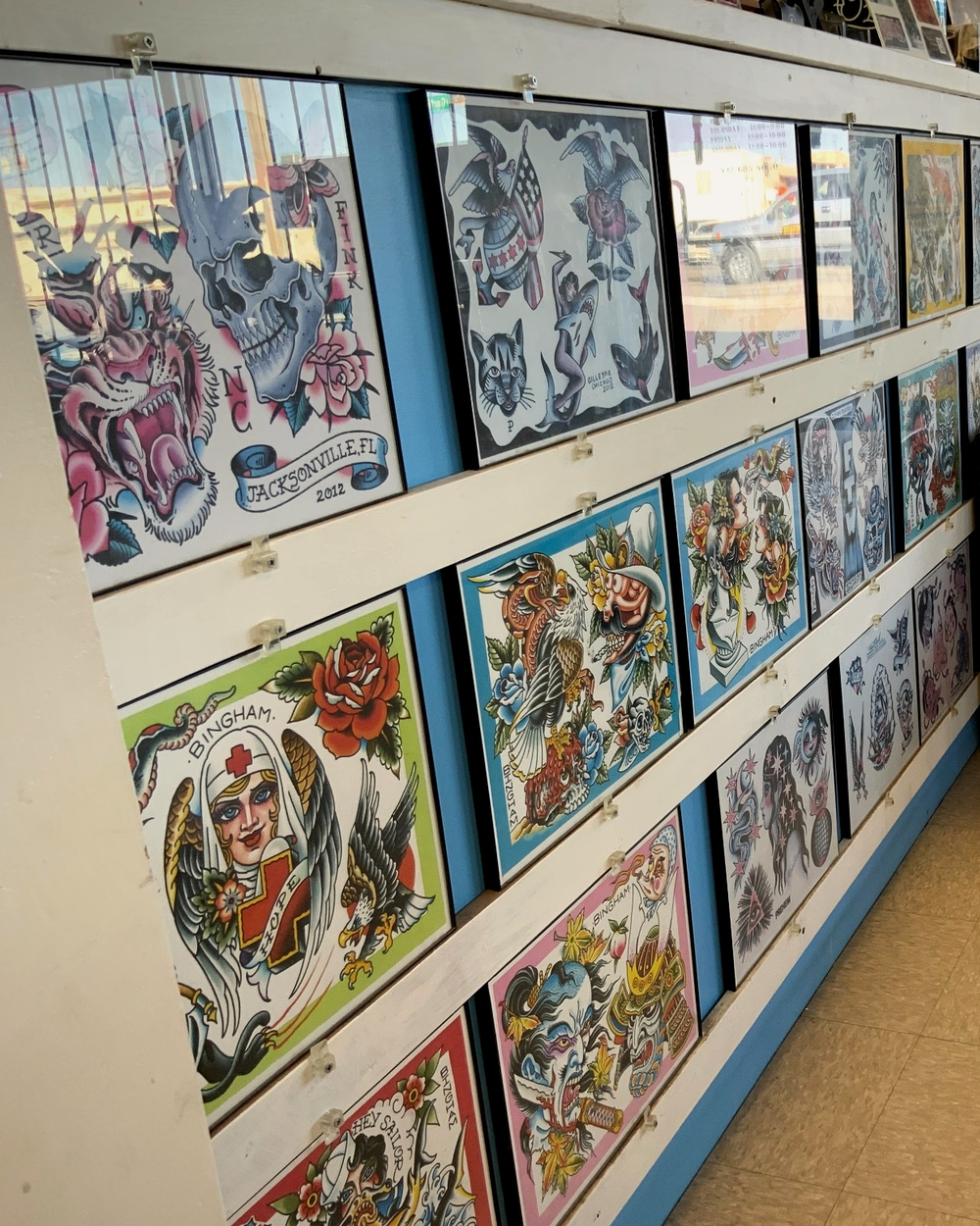 A long wall of framed flash sheets above the waiting bench