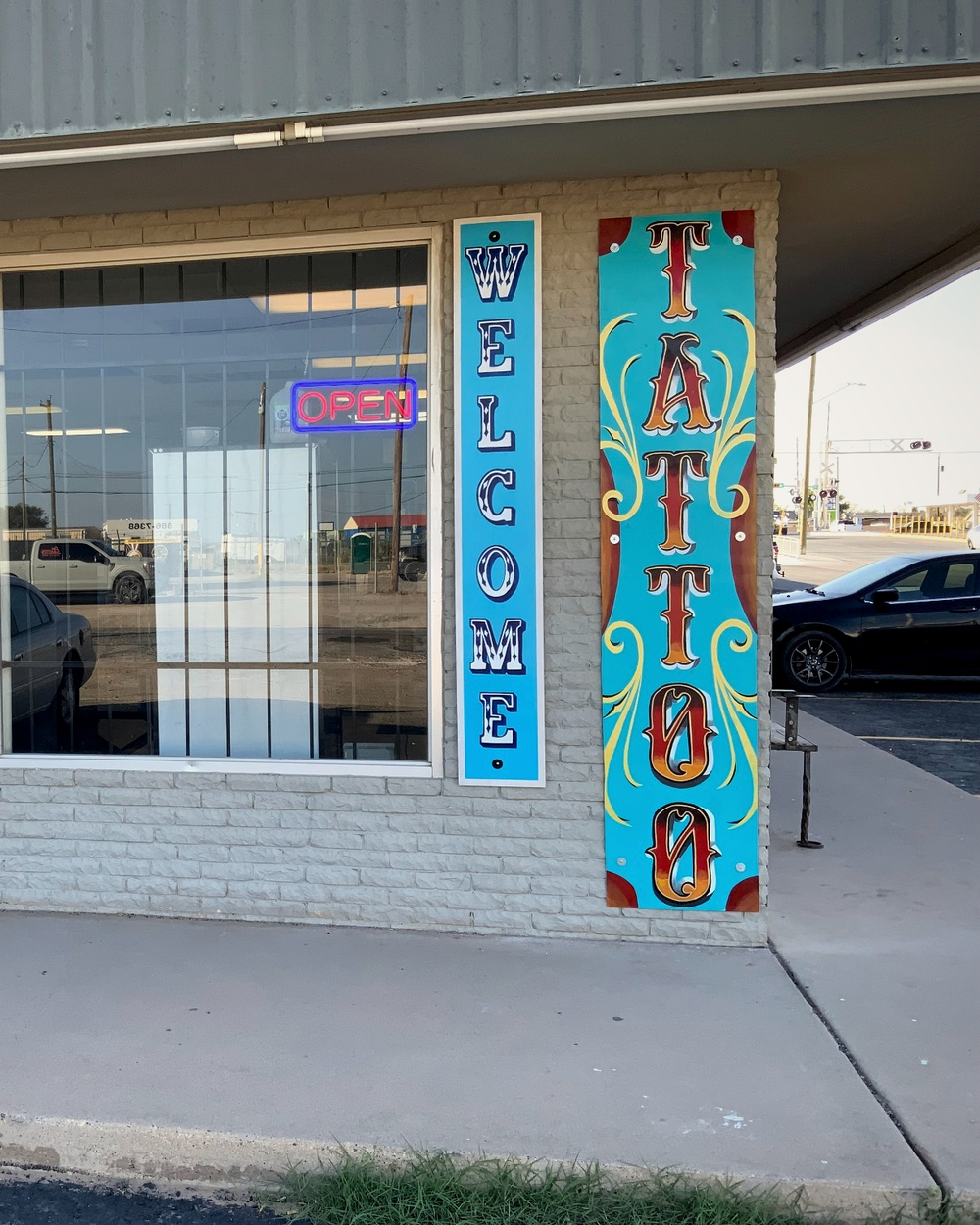 The storefront window with painted Tattoo, Walk-Ins, and Welcome lettering