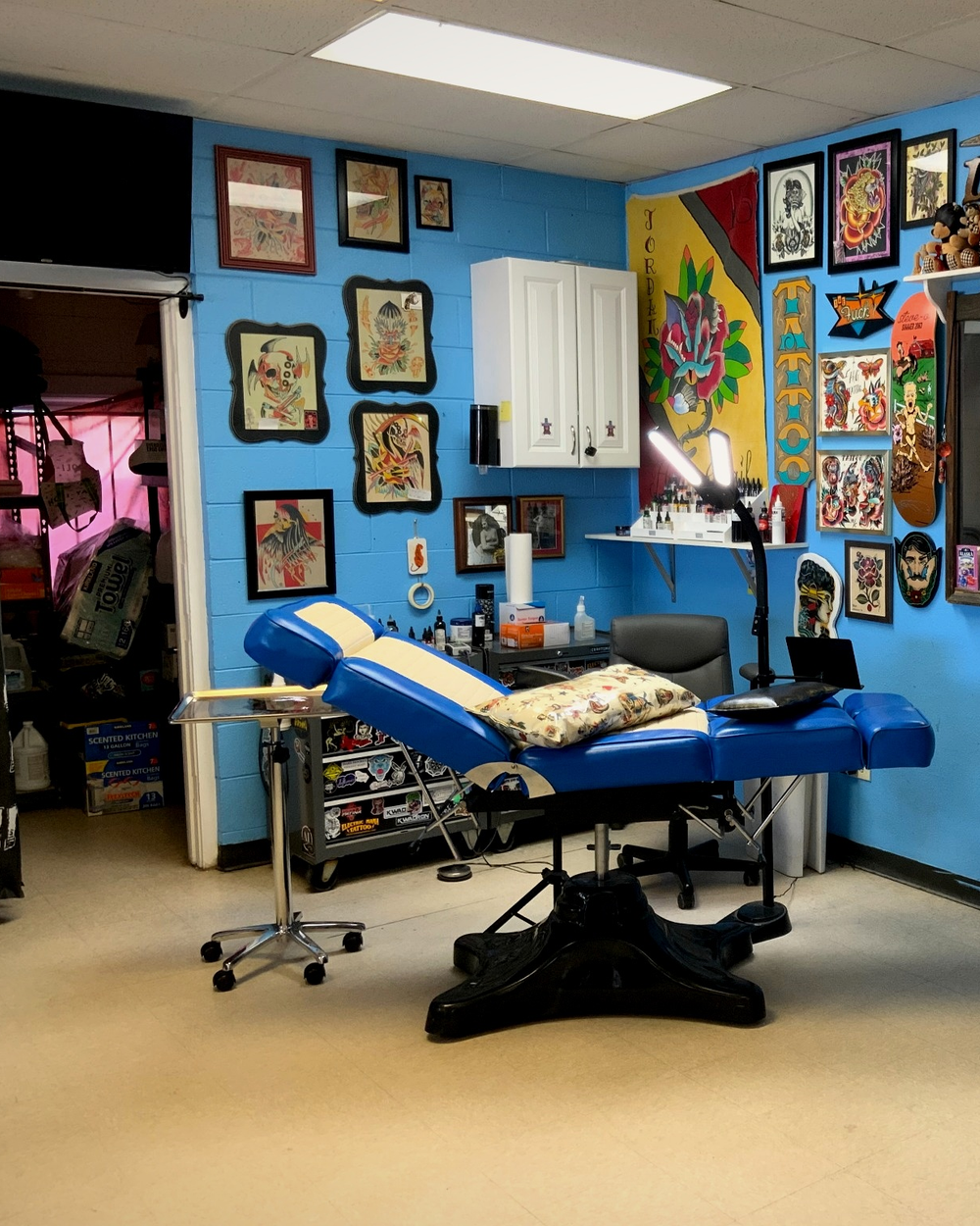A tattoo station with the yellow Holy Grail Tattoo banner and walls of framed flash